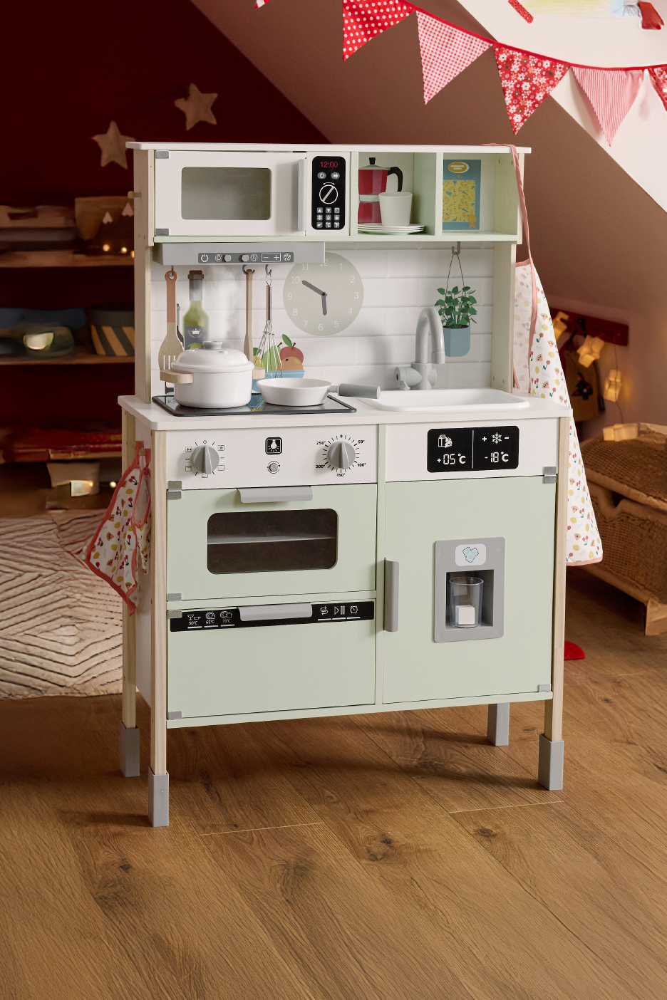 Μια μοντέρνα ξύλινη παιδική κουζίνα με φούρνο μικροκυμάτων, φούρνο και ψυγείο σε παιδικό δωμάτιο.