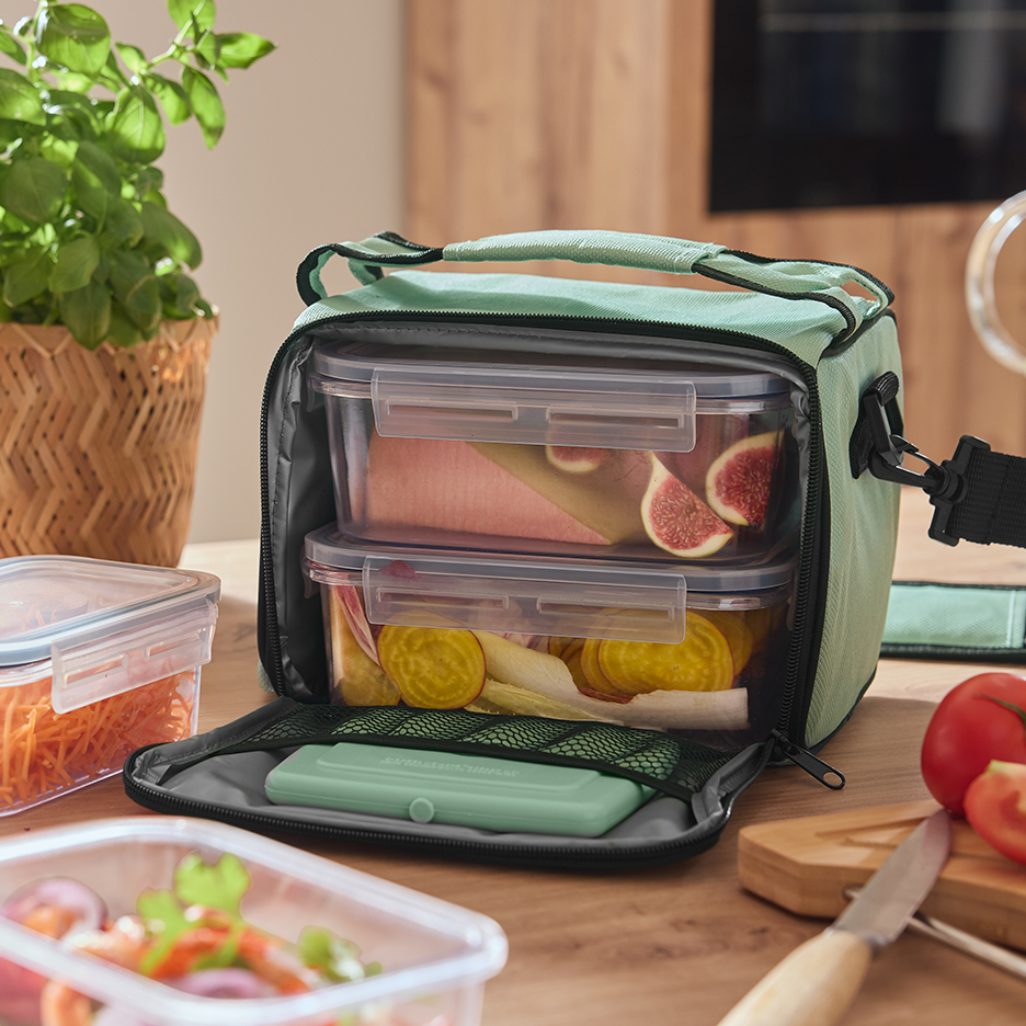 Τσάντα φαγητού με δοχεία γεμάτα σύκα, λαχανικά και σαλάτα σε ξύλινο τραπέζι.