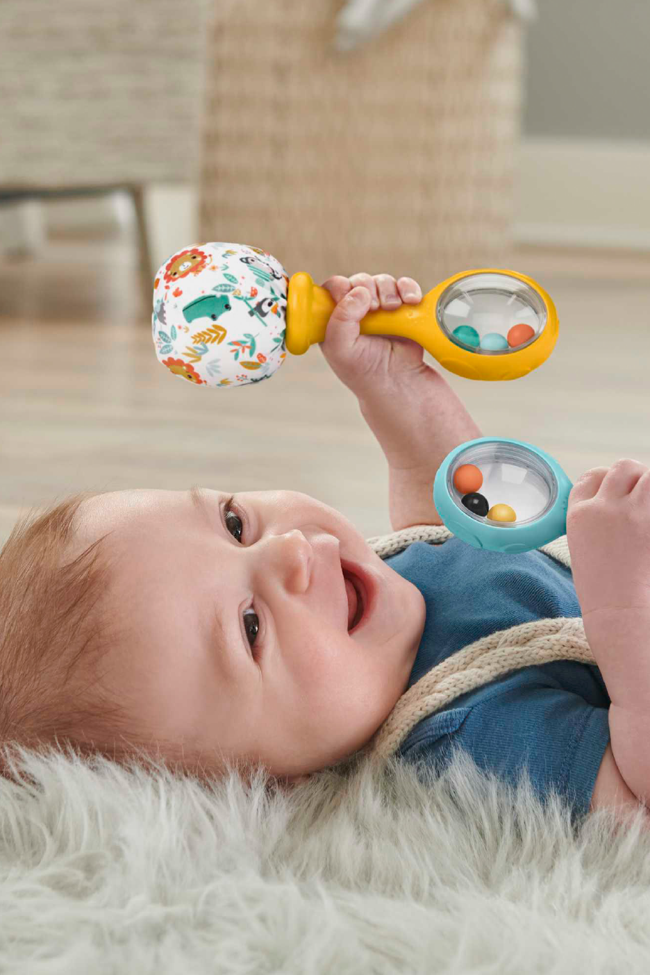 Ευτυχισμένο μωρό παίζει με δύο πολύχρωμες κουδουνίστρες σε ένα χνουδωτό χαλί.