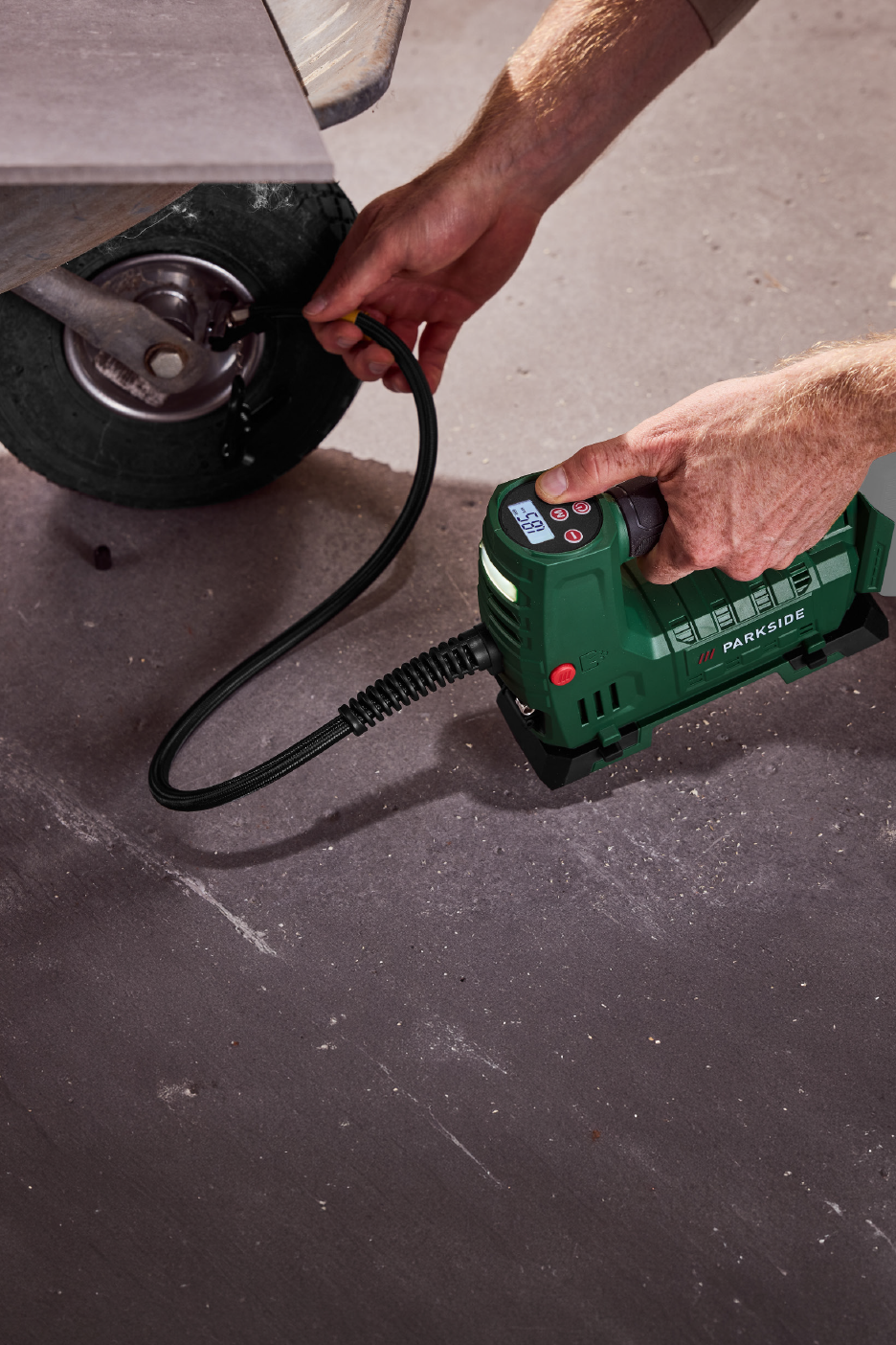 Άνδρας φουσκώνει ένα μικρό ελαστικό με έναν πράσινο φορητό αεροσυμπιεστή.