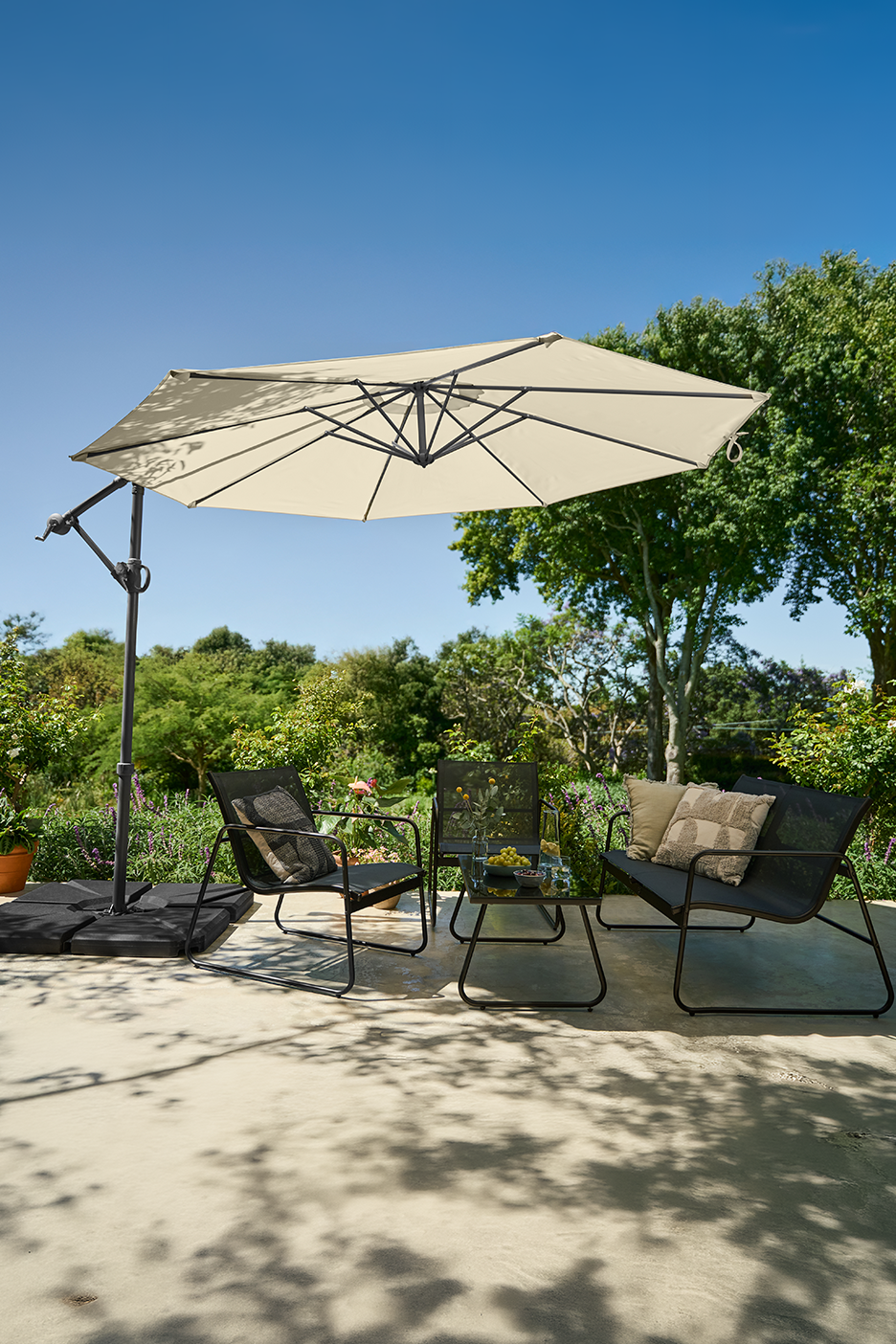 Σετ βεράντας με ομπρέλα προβόλου, δύο καρέκλες και ένα μικρό τραπέζι μια ηλιόλουστη μέρα.