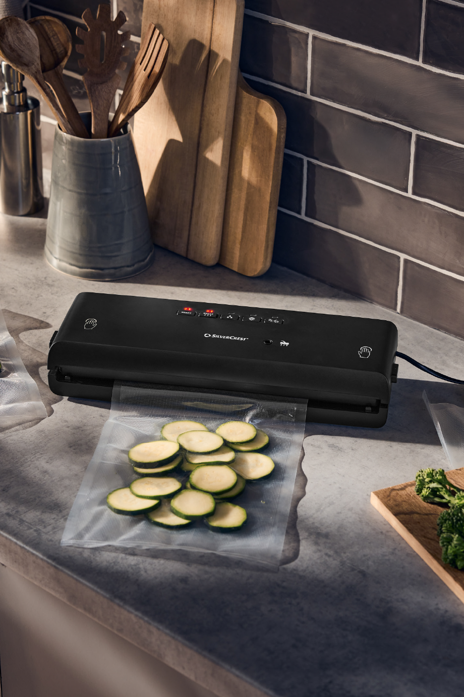 Συσκευή κενού τροφίμων με κολοκυθάκια σε σακούλα σε πάγκο κουζίνας.