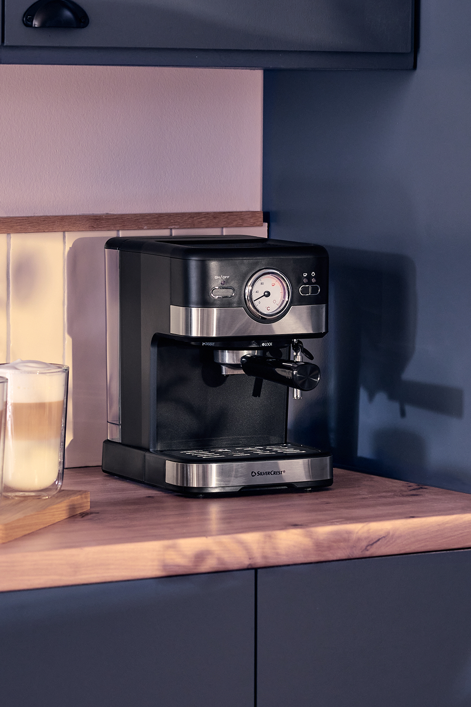 Μηχανή εσπρέσο σε ξύλινο πάγκο με ένα latte macchiato σε ποτήρι.