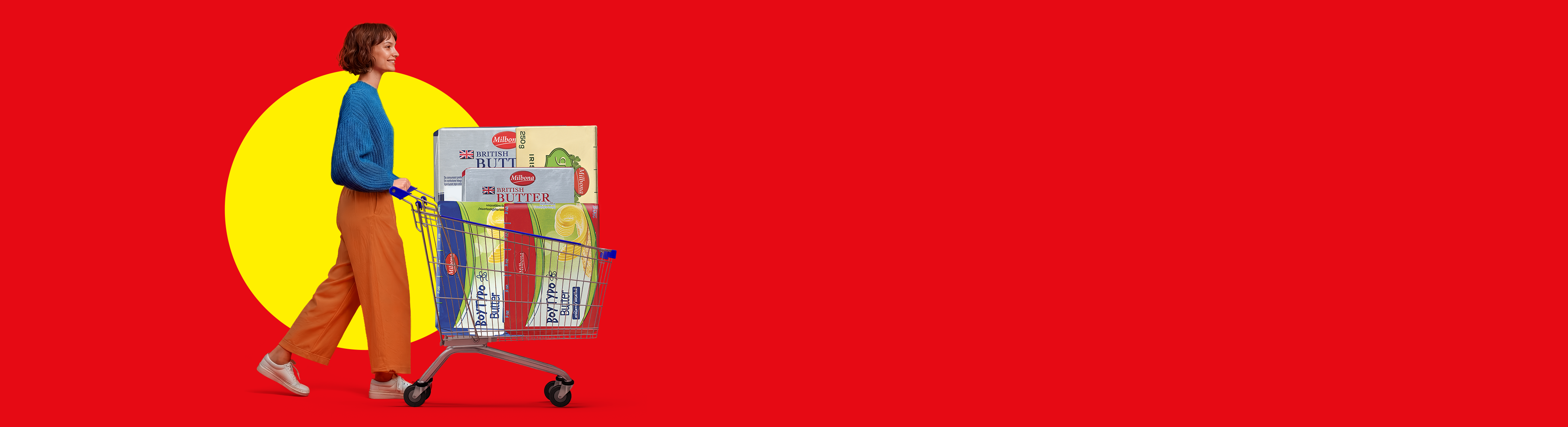 Μια γυναίκα σπρώχνει ένα καρότσι γεμάτο βούτυρο, μπροστά από ένα κόκκινο και κίτρινο φόντο.