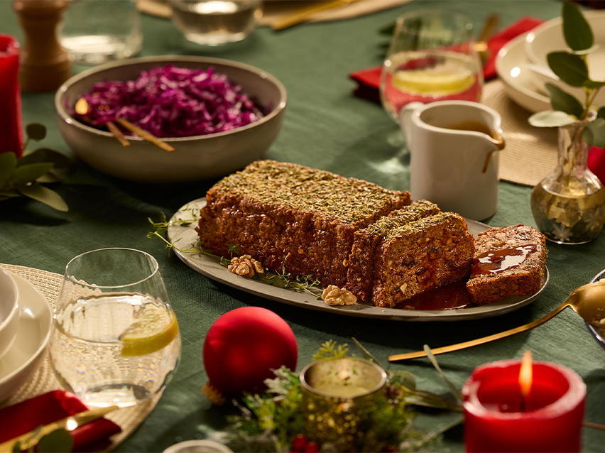 Χριστουγεννιάτικο δείπνο με ψητό καρύδι, κόκκινο λάχανο και γιορτινή διακόσμηση σε πράσινο τραπεζομάντιλο.