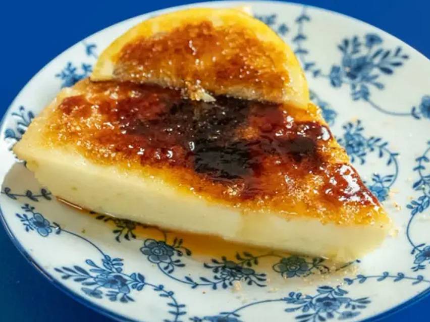 Φέτα κρεμ μπρουλέ με καραμελωμένη ζάχαρη και μια φέτα λεμόνι σε ένα πιάτο με σχέδια.