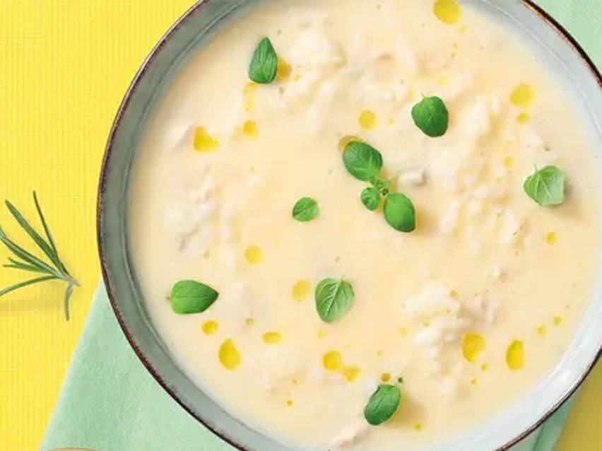 Κρεμώδης σούπα με μυρωδικά και σταγόνες λαδιού σε μπολ, σε κίτρινο φόντο με πράσινη πετσέτα.