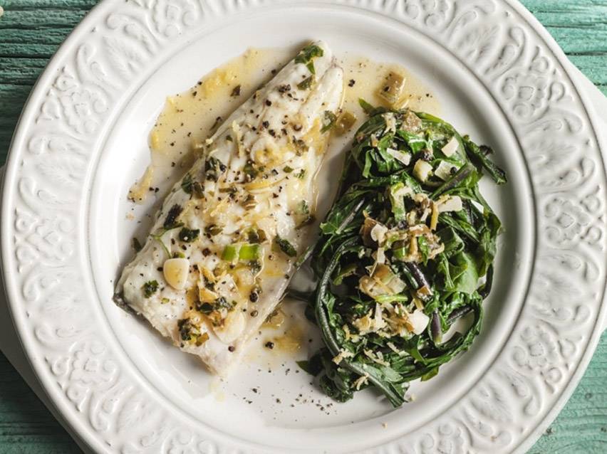 Λευκό φιλέτο ψαριού με πράσινα λαχανικά και σάλτσα σε λευκό πιάτο