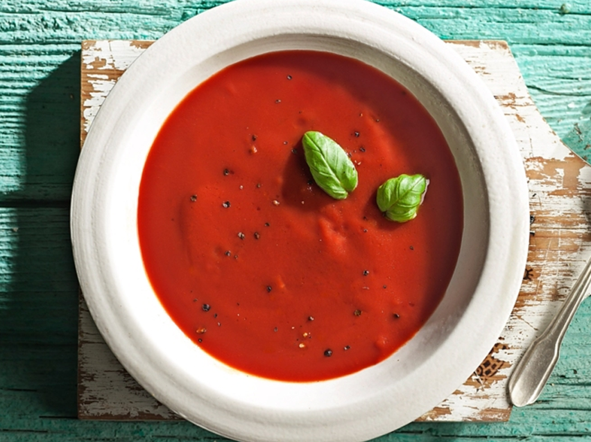Tomato soup with basil in a white bowl.